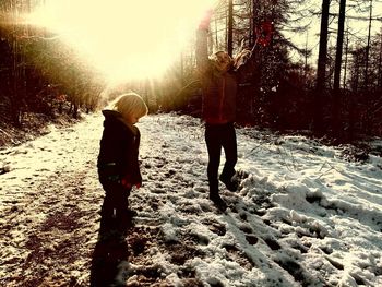 Rear view of mother and daughter walking on snow