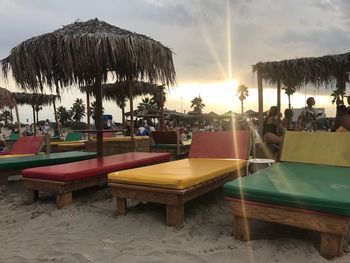 Chairs and tables on beach against sky during sunset