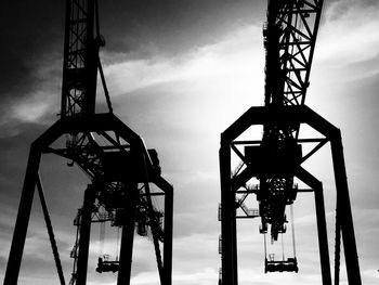 Low angle view of crane against cloudy sky