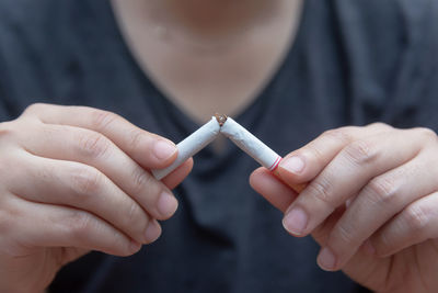 Close-up of man holding broken cigarette