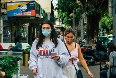 Portrait of friends standing on street in city