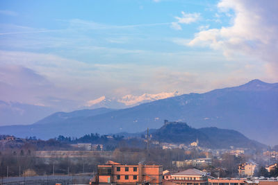 Scenic view of townscape by mountains against sky