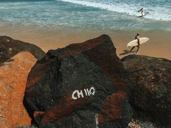 People standing on rocks at sea shore