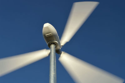 Low angle view of wind turbine against clear blue sky