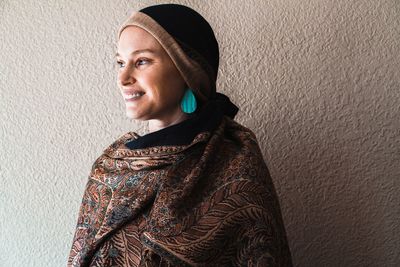 Portrait of smiling young woman standing against wall