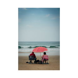 Rear view of people on beach against sky