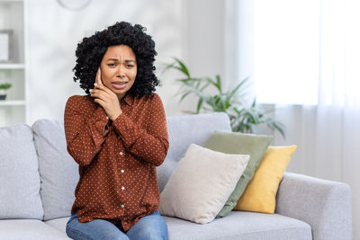 Portrait of young woman sitting on sofa at home