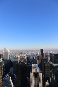 Aerial view of buildings in city against clear blue sky