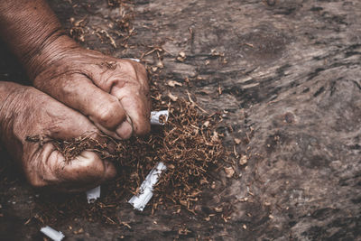 Cropped hands crumpling cigarettes outdoors