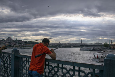 Rear view of man standing on bridge over river