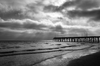 Bridge over calm sea against sky