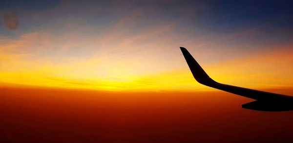 Silhouette airplane against sky during sunset