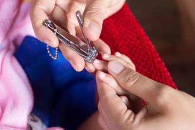 Cropped hand cutting child fingernails at home