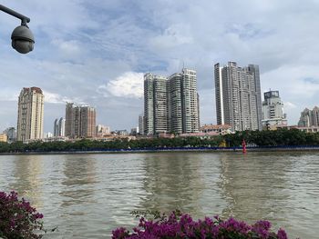 Scenic view of river by buildings against sky