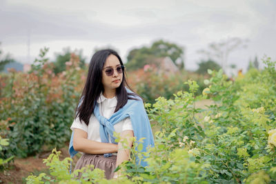 Young woman looking away while sitting on field