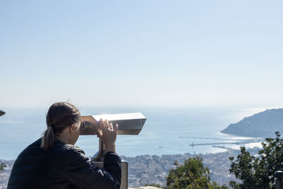 Rear view of woman photographing against sea