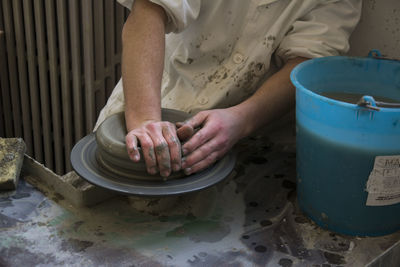 Midsection of man making earthenware in workshop