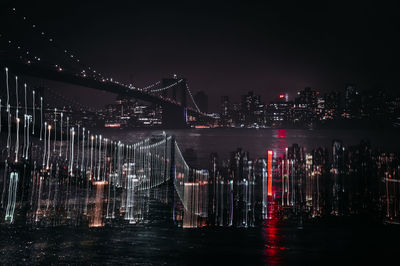 View of illuminated bridge over river at night