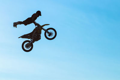 Low angle view of man jumping against sky