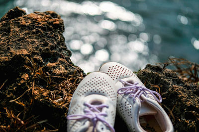 Close-up of shoes on cliff against sea