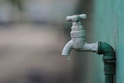 Close-up of water dripping out of faucet against wall