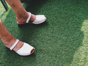 Close-up of woman with dirty legs wearing shoes on grass