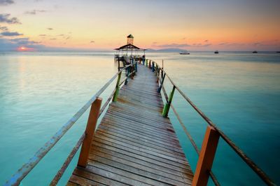 Pier over sea against sky during sunset