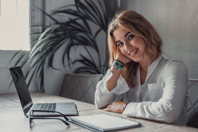 Young woman using mobile phone while sitting on table