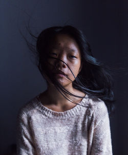 Portrait of woman sitting by wall at home