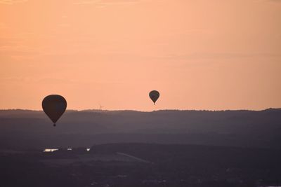 Hot air balloon flying over landscape against sky during sunset