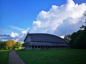 House on field by houses against sky