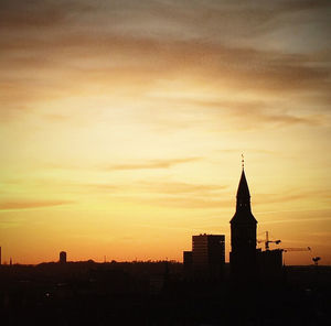 Silhouette of buildings against cloudy sky at sunset