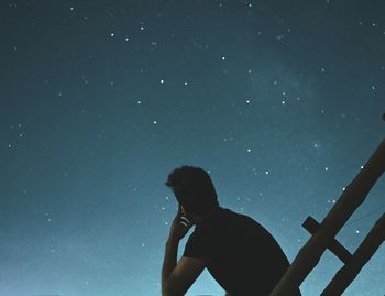 Rear view of silhouette man standing against sky at night