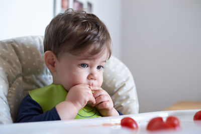 Little baby having tomatoes in the high chair