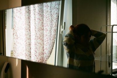 Rear view of people standing by window at home