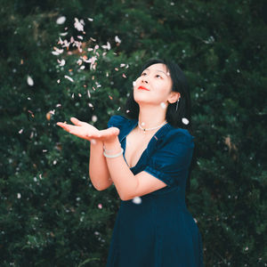 Portrait of young woman standing against trees