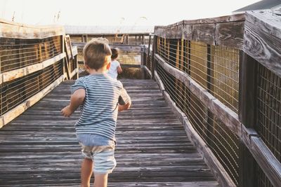 Full length rear view of man standing on bridge