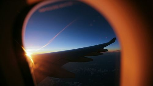 Close-up of airplane wing against sky during sunset