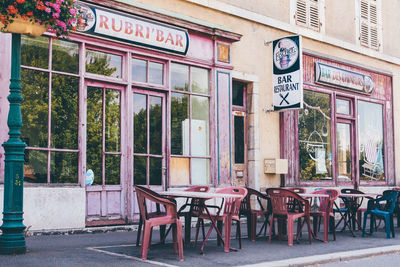 Empty chairs and tables at sidewalk cafe against building