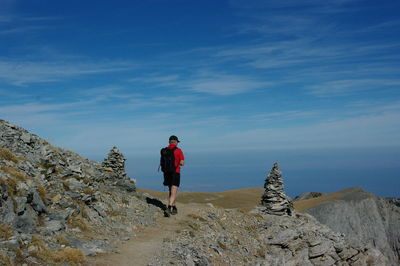 Rear view full length of man walking on mountain against sky