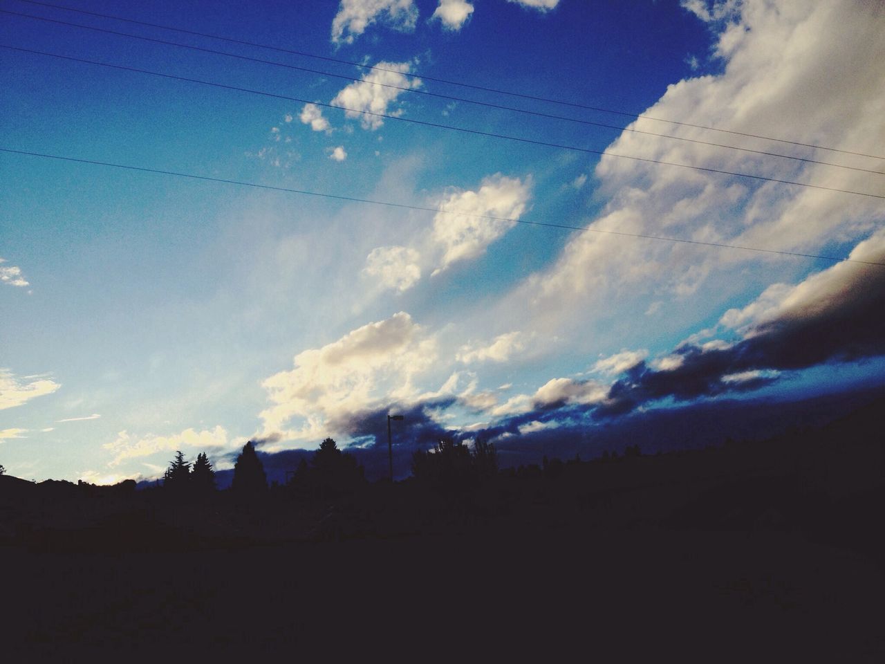 silhouette, power line, sky, electricity pylon, electricity, low angle view, building exterior, built structure, blue, cloud - sky, architecture, power supply, cable, cloud, dusk, vapor trail, nature, fuel and power generation, scenics, outdoors