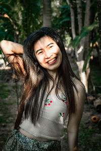 Portrait of smiling woman standing at forest