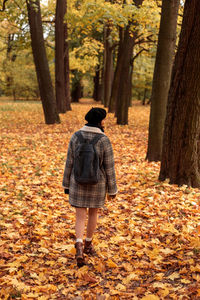 Rear view of woman walking in forest during autumn