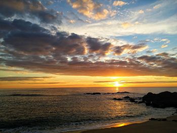 Scenic view of sea against dramatic sky during sunset