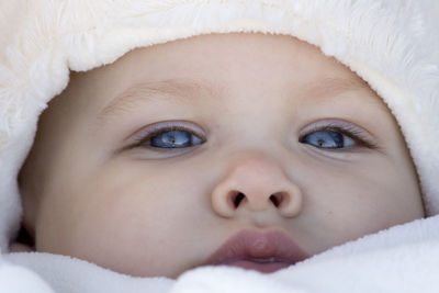 Close-up portrait of baby girl lying on bed