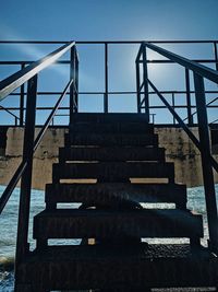 Low angle view of steps leading towards sea against sky