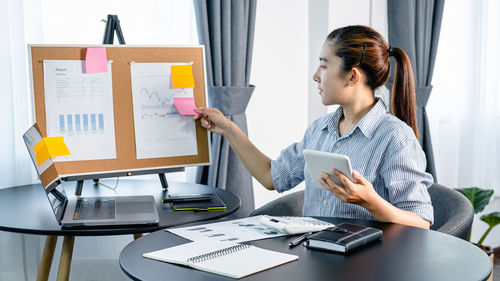 Side view of woman using digital tablet while working at office