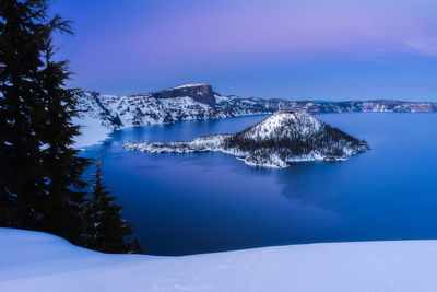Crater lake and wizard island in the snow at sunset