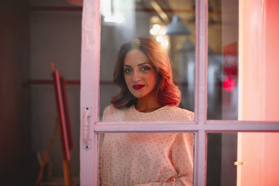 Portrait of young woman looking through window