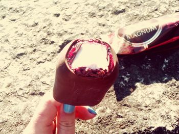 Close-up of hand holding sunglasses on sand